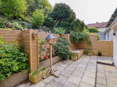 An outdoor patio area with tiled flooring wooden fencing and various plants in pots and planters at Buzzards View in Dyserth