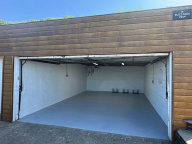 An empty garage with a concrete floor and white walls at Buzzards View in Dyserth