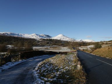 A road with snow patches and mountains in the background at Old Cottage in Oxen Park near Ulverston