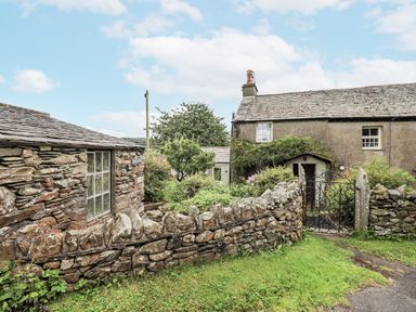An outdoor area with a cottage and garden at The Old Cottage in Oxen Park near Ulverston