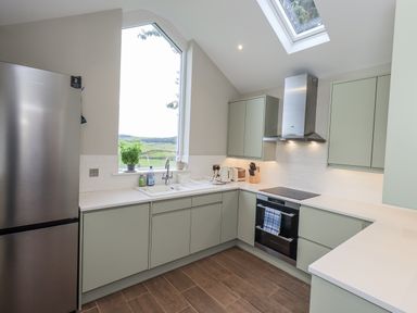 A kitchen with a refrigerator, sink, and oven at The Old Cottage in Oxen Park near Ulverston