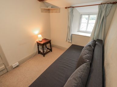 A bedroom with a couch and a lamp at The Old Cottage in Oxen Park near Ulverston