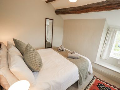 A bedroom with a bed and towels at Old Cottage in Oxen Park near Ulverston