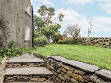 A garden with stone steps and a tree at Old Cottage in Oxen Park near Ulverston