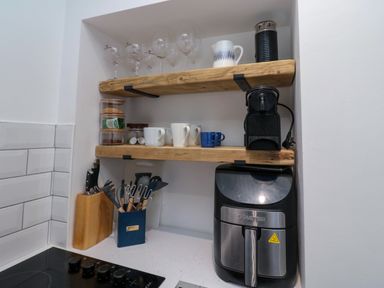 Wooden shelves with glasses cups and a coffee machine above an air fryer in a kitchen alcove at Number Ten in Amble