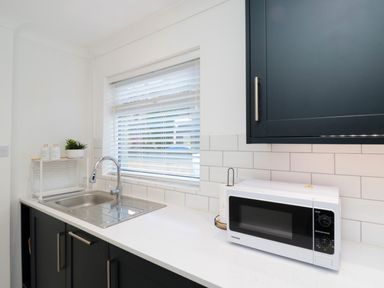 A kitchen sink with a faucet next to a microwave on a countertop at Number Ten in Amble