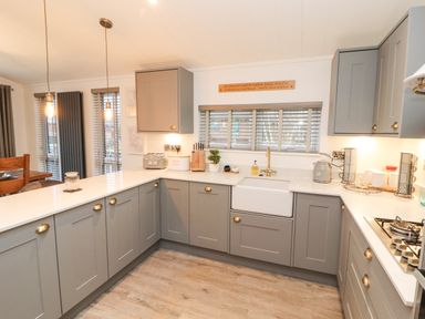 A kitchen with grey cabinets white countertops a sink and hanging lights at 12A Lake Escape in Carnforth