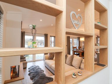 A living room with a sofa fireplace and decorative wooden shelving at 12A Lake Escape in Carnforth