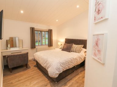 A bedroom with a bed desk chair and window with curtains at 12A Lake Escape in Carnforth