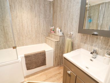 A bathroom with a bathtub a sink a mirror and toiletries at 12A Lake Escape in Carnforth