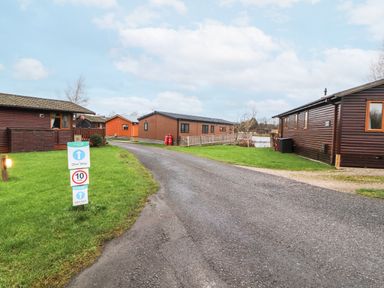 A road with a one way and 10 mph speed limit sign near wooden cabins at 12A Lake Escape in Carnforth