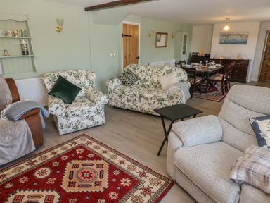 A living room with floral armchairs a gray recliner a red patterned rug and a dining table at Chapel Hill House Chapel Hill near Pembroke