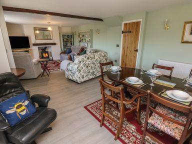 A dining area with set table and a living room with sofas and a wood burning stove at Chapel Hill House in Chapel Hill near Pembroke
