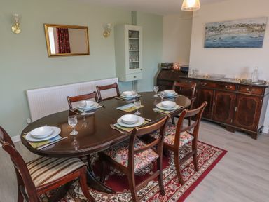A dining room with a dark wooden table set for six with glassware and plates at Chapel Hill House in Chapel Hill near Pembroke