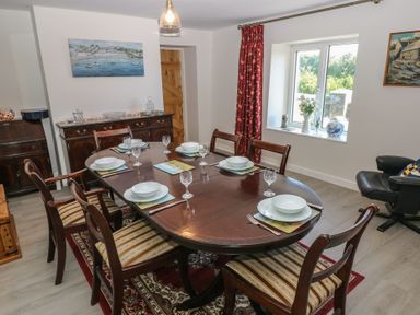 A dining room with a wooden table set for six people and chairs at Chapel Hill House in Chapel Hill near Pembroke