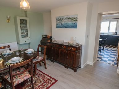 A dining room with a wooden table and chairs a sideboard with glassware and a painting on the wall at Chapel Hill House Chapel Hill near Pembroke