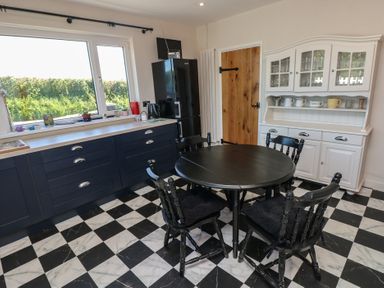 A kitchen with black and white checkered floor a round black table with four chairs black cabinets a white cupboard and a window at Chapel Hill House Chapel Hill near Pembroke