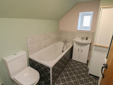 A bathroom with a toilet bathtub sink cabinet and patterned floor tiles at Chapel Hill House in Chapel Hill near Pembroke