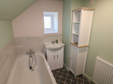 A bathroom with a bathtub sink cabinet storage unit and radiator at Chapel Hill House Chapel Hill near Pembroke