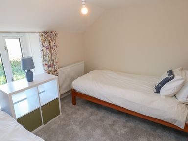A bedroom with two single beds a white cubed shelf with a lamp and a floral curtain at Chapel Hill House in Chapel Hill near Pembroke