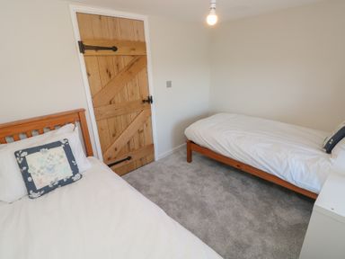 A bedroom with two single beds a wooden door and grey carpet at Chapel Hill House Chapel Hill near Pembroke