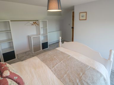 A bedroom with a white bed frame a bedside lamp and shelves with hangers at Chapel Hill House in Chapel Hill near Pembroke