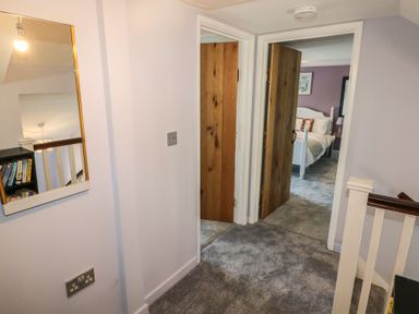 A hallway with carpeted floor with two wooden doors leading to rooms and a mirror on the wall at Chapel Hill House Chapel Hill near Pembroke