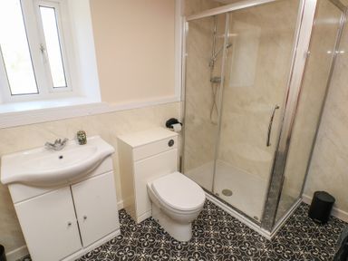 A bathroom with a sink, a toilet, a glass shower enclosure, and patterned floor tiles at Chapel Hill House in Chapel Hill near Pembroke