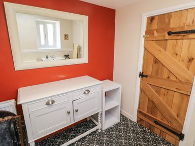 A room with a wooden door white cabinet a mirror and patterned floor tiles at Chapel Hill House in Chapel Hill near Pembroke