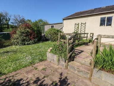 A garden area with grass and flowers next to a paved patio with wooden railings at Chapel Hill House in Chapel Hill near Pembroke