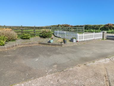 A paved driveway with a white picket fence and potted plants near a green wooden fence in a rural setting at Chapel Hill House in Chapel Hill near Pembroke