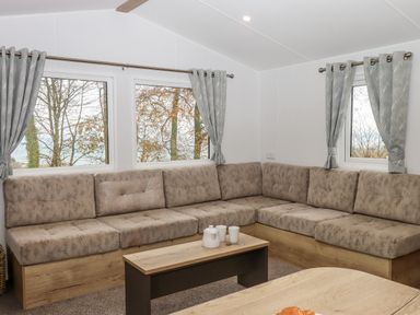 A corner seating area with cushioned benches and a wooden coffee table with cups and teapot at 5 Manor Park in Bucks Cross Bideford