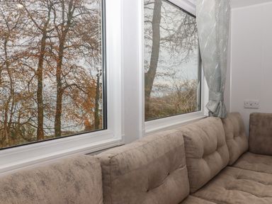 A corner sofa next to two large windows overlooking trees at 5 Manor Park in Bucks Cross Bideford