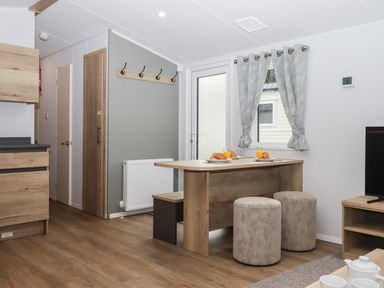A dining area with a wooden table set with croissants and orange juice and two round stools at 5 Manor Park in Bucks Cross Bideford