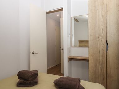 A bedroom with an open door a wooden wardrobe with a mirror and folded towels on a bed at 5 Manor Park Bucks Cross Bideford