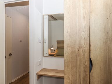 A hallway with a wooden wardrobe and mirror showing a bedside table and lamp at 5 Manor Park in Bucks Cross Bideford