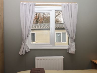 A window with light gray curtains and a radiator below in a room at 5 Manor Park Bucks Cross Bideford
