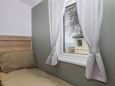 A bedroom with a bed next to a window with curtains at 5 Manor Park Bucks Cross Bideford