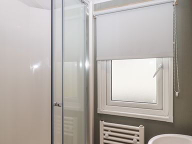 A bathroom with a shower enclosure a frosted window with a roller blind and a heated towel rail at 5 Manor Park Bucks Cross Bideford
