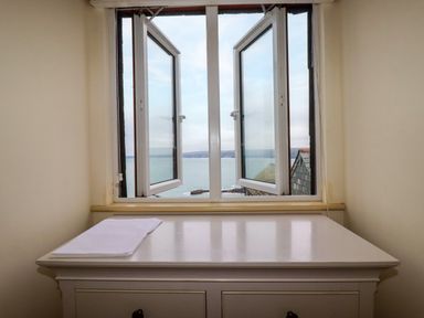 A white desk with papers on it in front of a window with an ocean view at Blue Horizon in Port Isaac