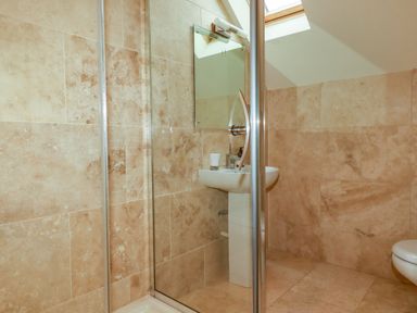 A bathroom with a glass shower enclosure sink with a mirror and skylight at Blue Horizon in Port Isaac