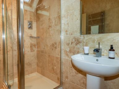 A bathroom with a glass shower enclosure and a white sink with a faucet and soap dispenser at Blue Horizon in Port Isaac