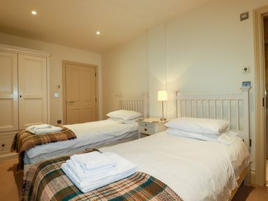 A bedroom with two single beds bedside table with lamp and wardrobe at Blue Horizon in Port Isaac