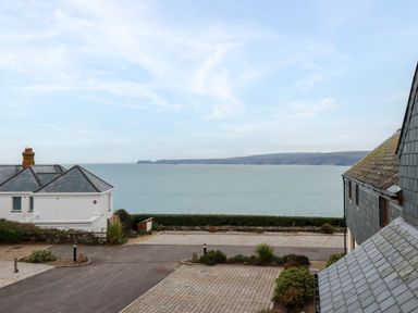 A view of the sea with houses and a paved driveway in the foreground at Blue Horizon in Port Isaac