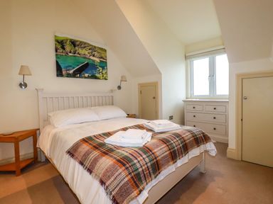 A bedroom with a double bed a wooden side table a chest of drawers and a window at Blue Horizon in Port Isaac