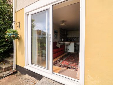 A living room with a sliding door and a couch at Garden View in Hillhead near Brixham