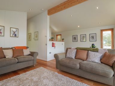 A living room with two grey sofas cushions framed prints and wooden floors at 3 Hedgerows in Lanreath