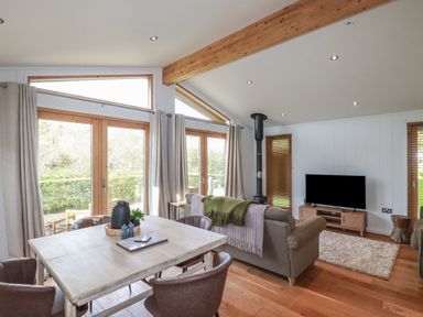 A living room with a dining table and chairs two sofas a TV and large windows at 3 Hedgerows in Lanreath