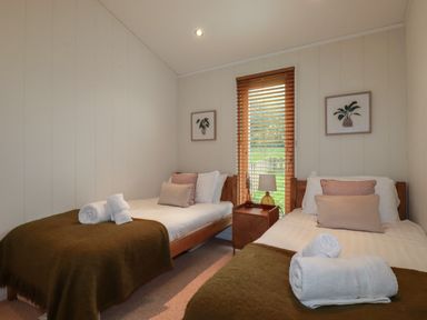 A bedroom with two single beds a wooden nightstand and a window with wooden blinds at 3 Hedgerows in Lanreath