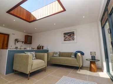 A living area with beige armchairs a sofa and a side table under a skylight at Little Victory in Pendeen